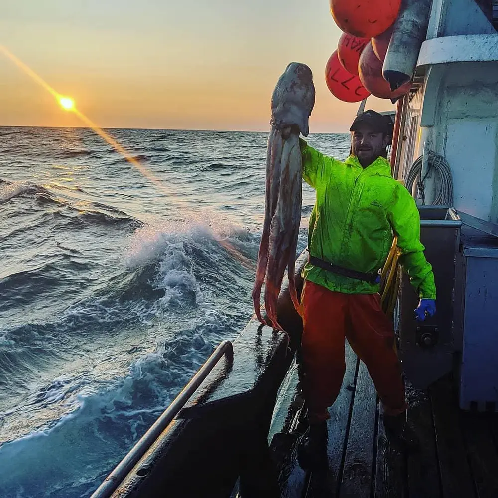 A fisherman on deck at sunset over open water, the ocean the mission is fighting for.